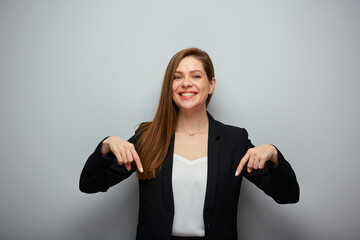 Smiling business woman in black suit pointing fingers down isolated portrait.