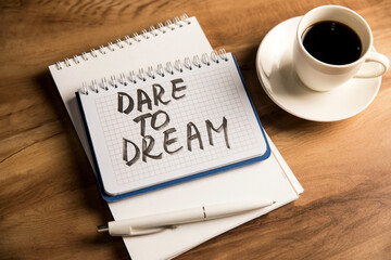 The inscription on the notepad dare to dream and a cup of coffee
