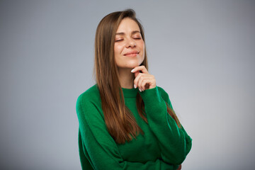 Thinking smiling young woman with closed eyes in green sweater. Isolated advertising portrait.