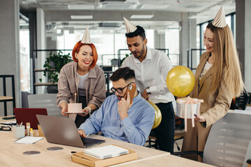 Surprise. Mixed race happy people celebrating a birthday of colleague in the modern office.