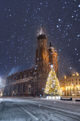 Krakow, Poland, snowy Main Market square, St Mary's church and Cloth Hall in the winter season, during Christmas fairs decorated with Christmas tree - 553321310