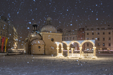 Main Square in Krakow with St Wojciech church during snowfall, winter night