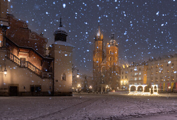 Fototapeta na wymiar Krakow, Poland, snowy Main Market square, St Mary's church and Cloth Hall in the winter season, during Christmas fairs decorated with Christmas tree