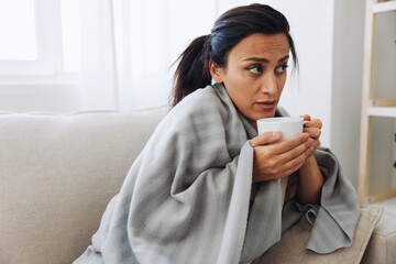 A woman with a cold pills is treated at home chooses which medicines to take and self-medicates, checks the expiration date while sitting at home on the couch, temperature, allergies and covid-19