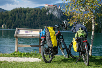 two bicycles with panniers parked on the shore of lake bled