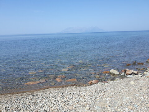 aegean seascape with stones in the shore and faraway samothraki - samothrace island