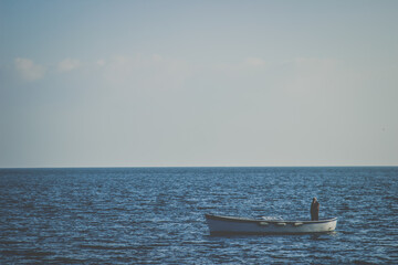 A lonely Fisherman in a small boat at the open blue sea on the coast of Naples, Italy 