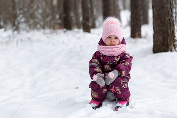 Fototapeta na wymiar A little girl sits on a stump in a winter snowy forest, New Year holidays, winter, snow.