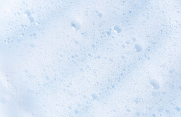 White foam texture with bubbles. Cosmetic soapy substance with bubbles. Creamy grainy macro backdrop. Cosmetic product foamy smudges and smears top view. White cleanser foam textured background.