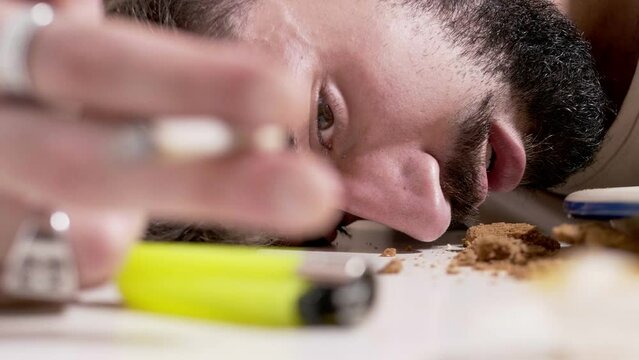 brutalized by drugs - man with his head resting on the table smokes a joint