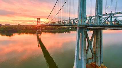 Pink and golden sunrise light behind stunning American bridge on Hudson River