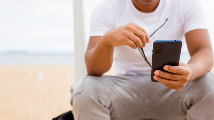 Front view portrait of a man with black skin checking cell phone in the street