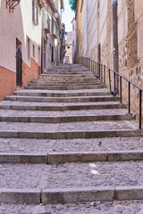 Fototapeta na wymiar Vertical photo of some stairs of a narrow old street in a village. Selective focus.