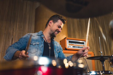 Excited drummer in recording studio. Caucasian middle aged stylish male drummer playing on his instrument indoor. High quality photo