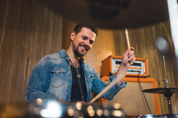 medium shot of a satisfied man playing drums in the studio, music concept recording studio. High...