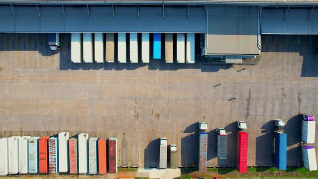 4K : Many of Semi-trailer trucks stand at the distribution center. cargo import export shipment. Industrial containers cargo shipment. consumption and transportation concept. aerial view footage.
