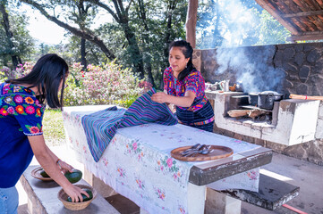 Madre e hija poniendo la mesa para comer. Familia indigena en la cocina. 