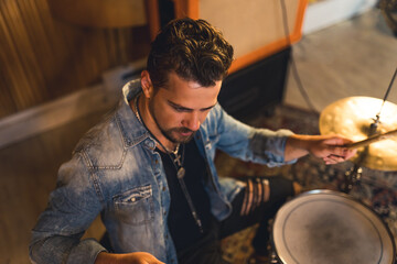 high-angle view of a drummer with curly hair sitting and playing on repetition, young musician. High quality photo