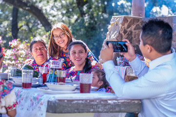 Padre haciendo una foto a su familia con el teléfono celular. Familia Hispana en la mesa del jardin de su casa., familia latina. 