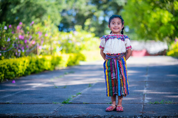 Retrato de una hermosa niña indígena con un colorido vestido. Dulce niña Hispana en el parque. Niña al aire libre.