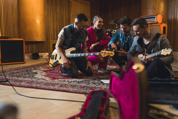 full shot of a music band members sitting on the floor on repetition, a guitar case in front of...