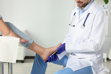 Male orthopedist fitting insole to patient's foot in hospital, closeup