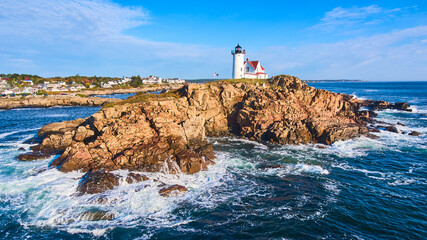Huge rocky island with lighthouse on Maine coast aerial with waves crashing over rocks