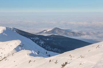The winter trail goes along a mountain ridge that rises beautifully above the clouds