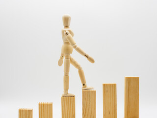 Maniquí de madera subiendo una escalera, aislado en blanco