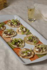 Chalupas, Typical Mexican dish made with tortillas, sauce, cheese, meat and lettuce on white tablecloth.