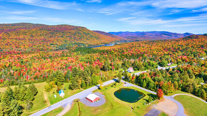 Aerial over road and endless colorful peak fall hills of New York