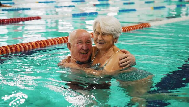 Active seniors concept. Happy elderly caucasian heterosexual married couple swimming in a pool breaststroke style. Leisure time activities for people of all ages. High quality 4k footage