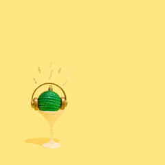 Green Christmas bauble with headphones, musical notes and violin keys in a frozen glass. Concept of Christmas, New Year and winter holidays celebration,  party, music and happiness. Good Vibes.