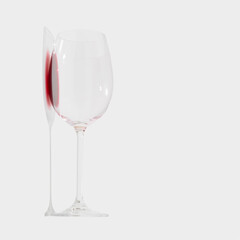 Minimal composition of glass with a few drops of red wine on white background. Love, party, drinking culture and celebration concept.