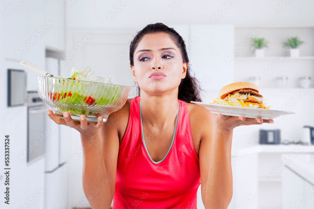 Wall mural unhappy woman glance at salad while choose foods