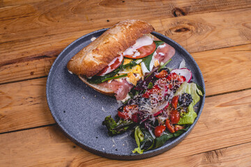 Emparedado de jamón acompañado de ensalada, queso, aderezo, vegetales y bebida cocktail 