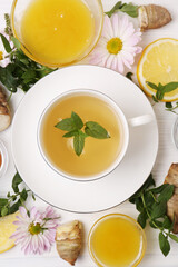 Flat lay composition with cup of delicious tea, honey and ginger on white wooden table