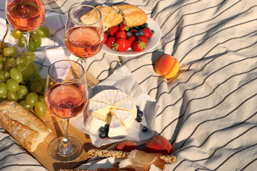 Fototapeta na wymiar Glasses of delicious rose wine and food on white picnic blanket