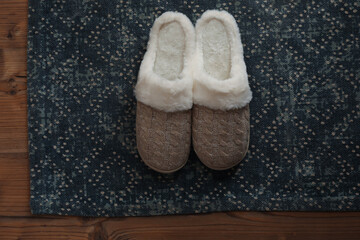 Stylish door mat and slippers on wooden floor, top view