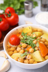 Tasty chickpea soup in bowl served on light grey table