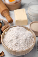 Fototapeta na wymiar Bowl of flour and other ingredients on white table