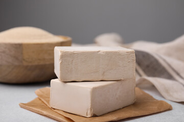 Blocks of compressed yeast on light gray table, closeup