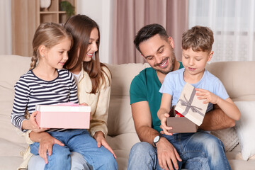 Happy family presenting each other with gifts on sofa at home