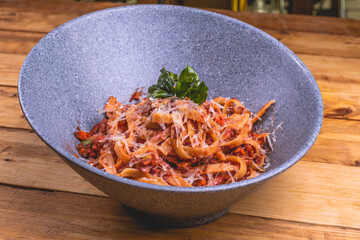 Plato de pasta alfredo, con queso gratinado, salsa en una mesa de madera.