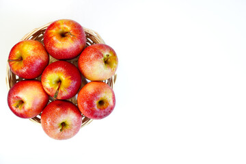 Red apples of the Gala variety in a basket, top view, white background, close-up, space for text