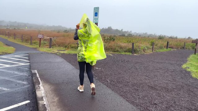 Woman in rain on outside of Mauna Loa volcano rim in Hawaii, cloudy day
