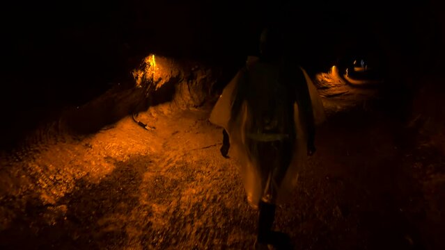 Mauna Loa volcano, woman walking down path in dark tunnel in Hawaii,