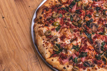 Pizza a la leña con ingredientes variados como carne, cebolla, pimiento, chorizo, jamón. 