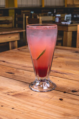 Colorida soda italiana de fresa con limón, tequila y hielo sobre una mesa de madera en un restaurante.
