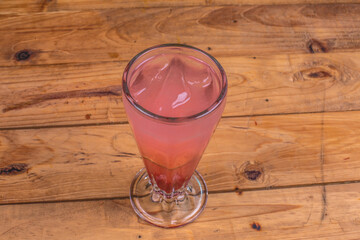 Colorida soda italiana de fresa con limón, tequila y hielo sobre una mesa de madera en un...